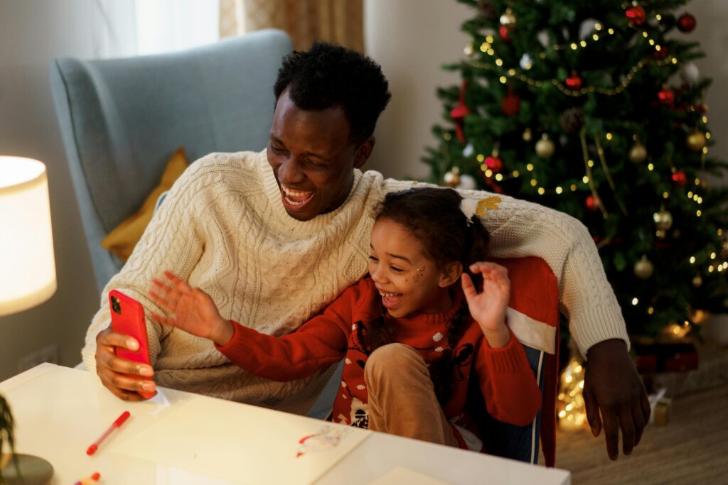 Father and daughter share joyous moments during Christmas, capturing memories indoors.